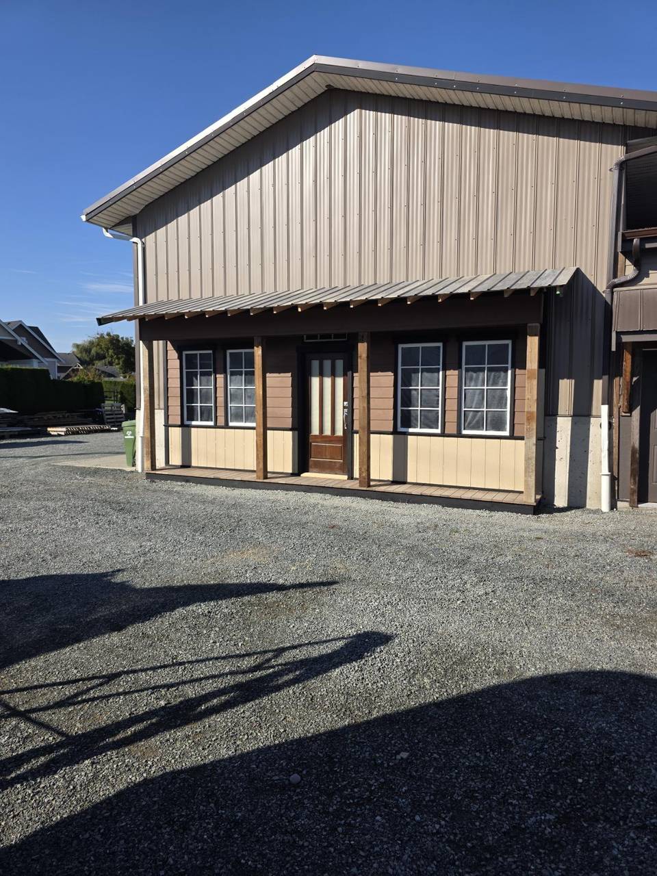 Metal building with a wood porch, brown siding, and a stained door