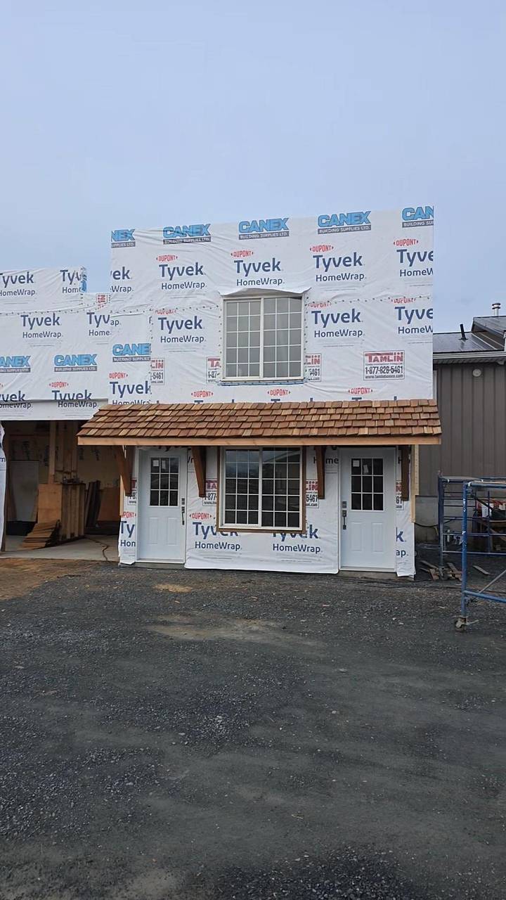 Cedar-shake porch finished over two doors, the walls still in house wrap