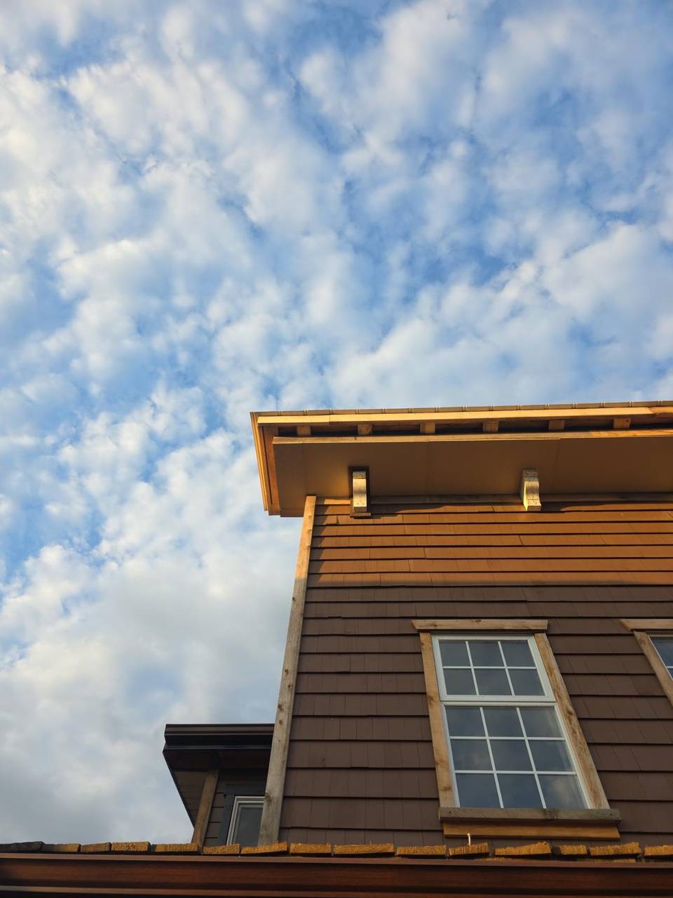 Soffit and corbels over a trimmed window on the brown siding