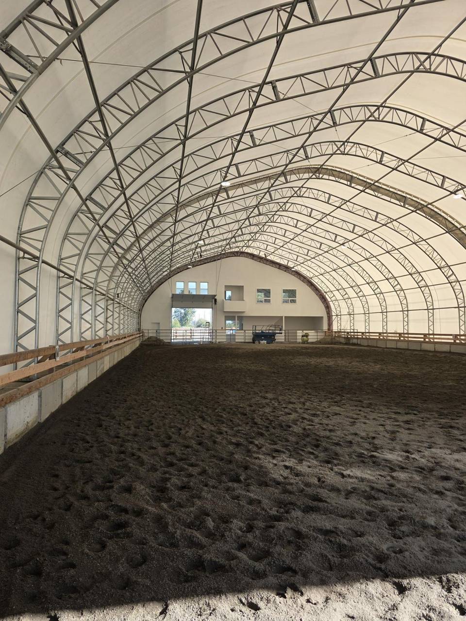 Indoor riding arena with a steel truss roof and fresh footing