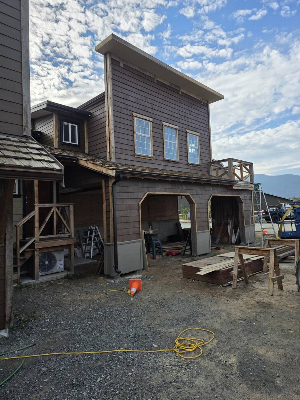 Arched bays under brown siding, with a wood rail on the stair