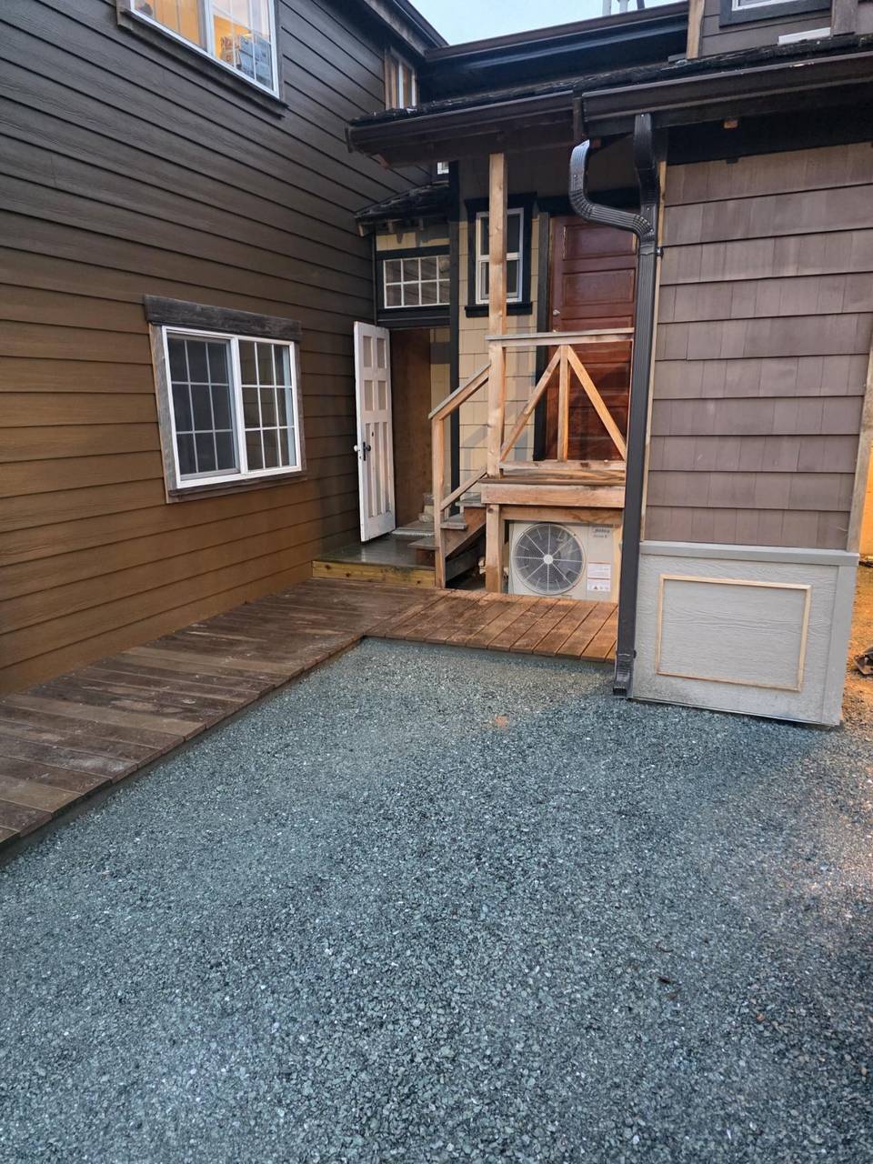 Side court with brown siding, a wood walkway, and a stair