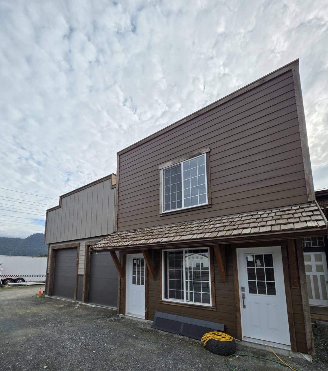 Brown siding, white doors, and a cedar-shake porch roof