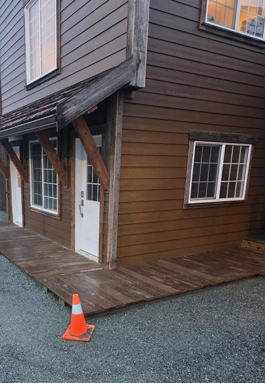 Wood porch deck under a shake awning on the brown house