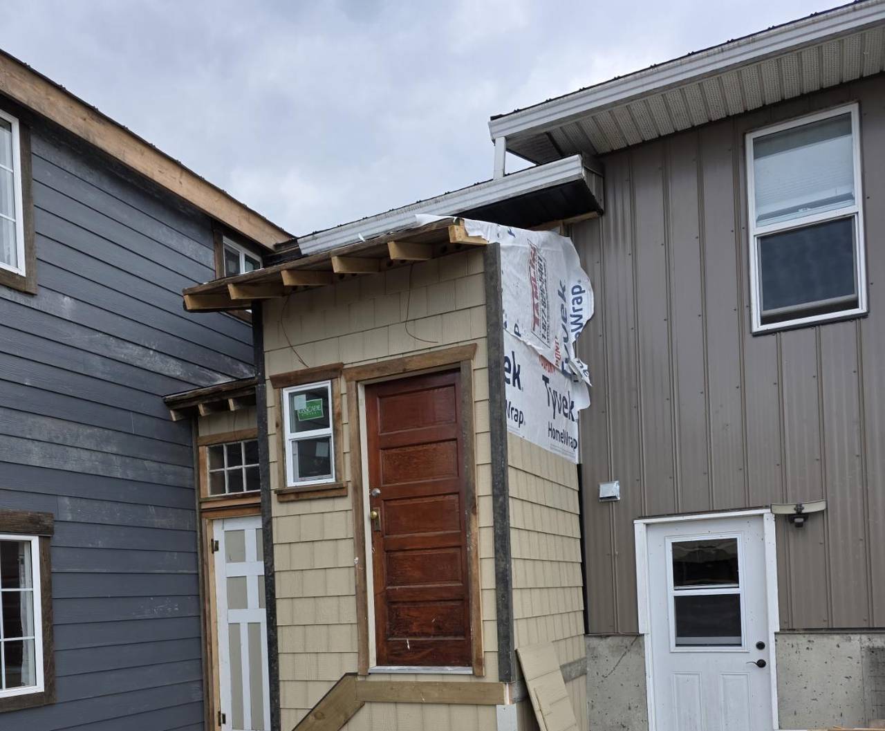 Shake siding and a stained door on the new entry between the houses