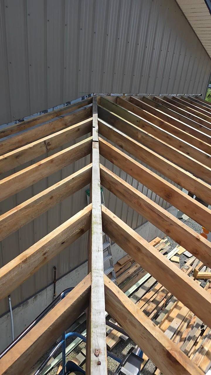 Rafters laid out for a porch roof against a metal wall