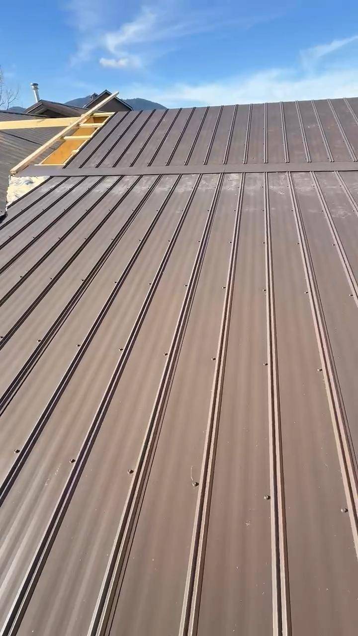 Brown metal roof panels locked in, with a dormer still open