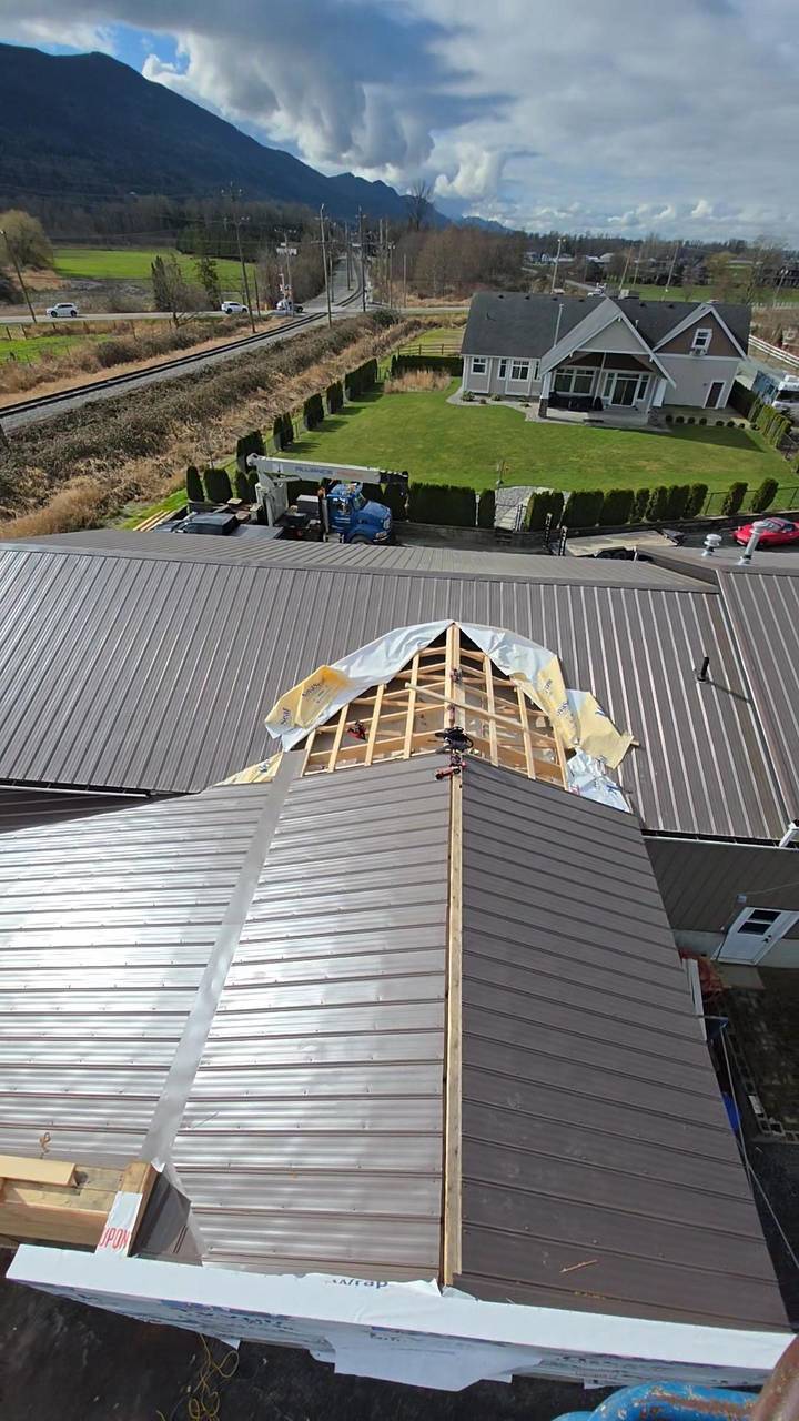 Metal roof with the gable still open, rafters and house wrap showing
