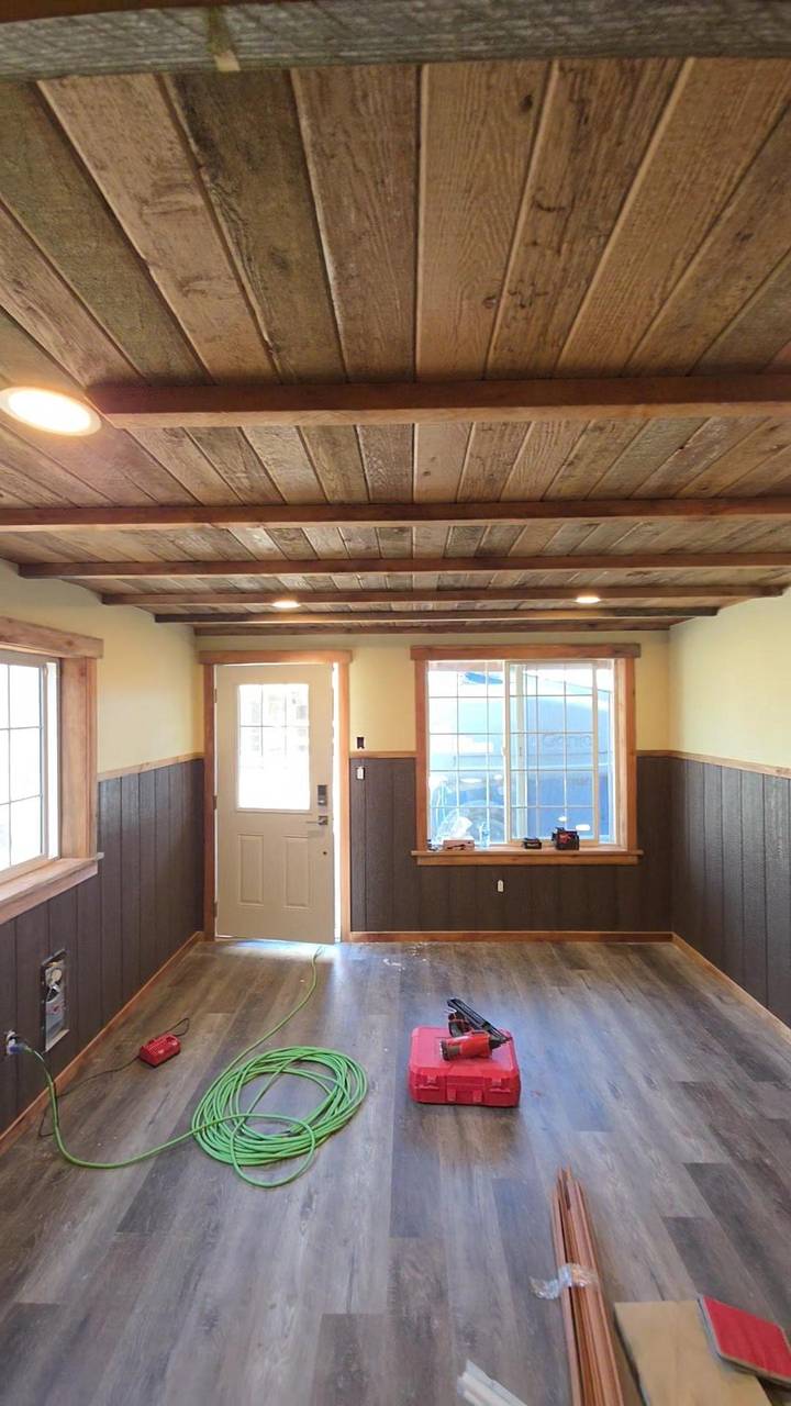 Finished room with a wood ceiling, dark wainscot, and a door to the yard