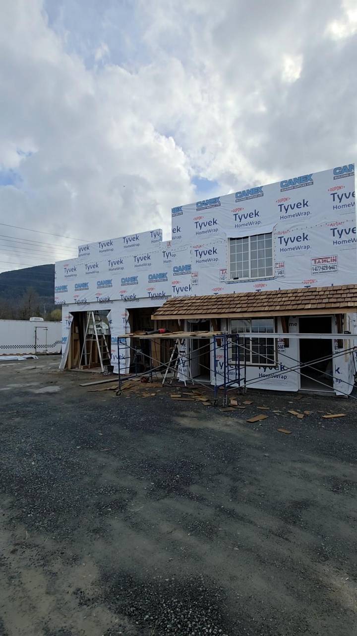 Cedar shakes going on a porch roof in front of a wrapped house