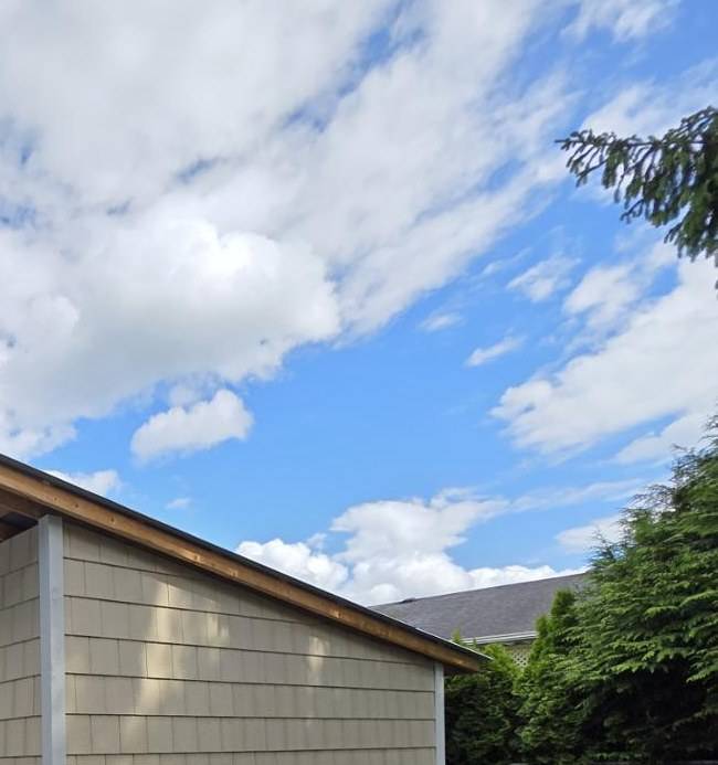 Garden shed in shake siding with the roof overhang framed