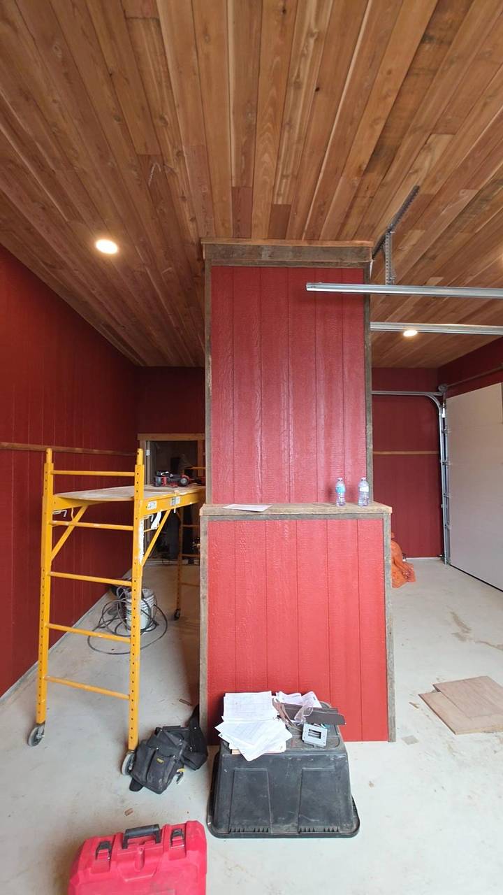 Red board half-wall inside a shop with a wood plank ceiling