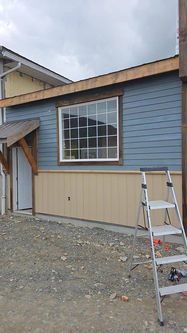 Blue lap siding over beige board, wood trim around the window