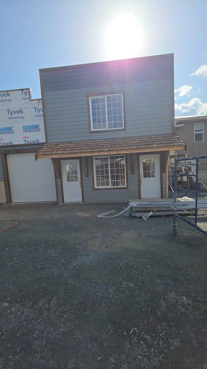 Grey siding finished on the addition, cedar-shake porch over two doors