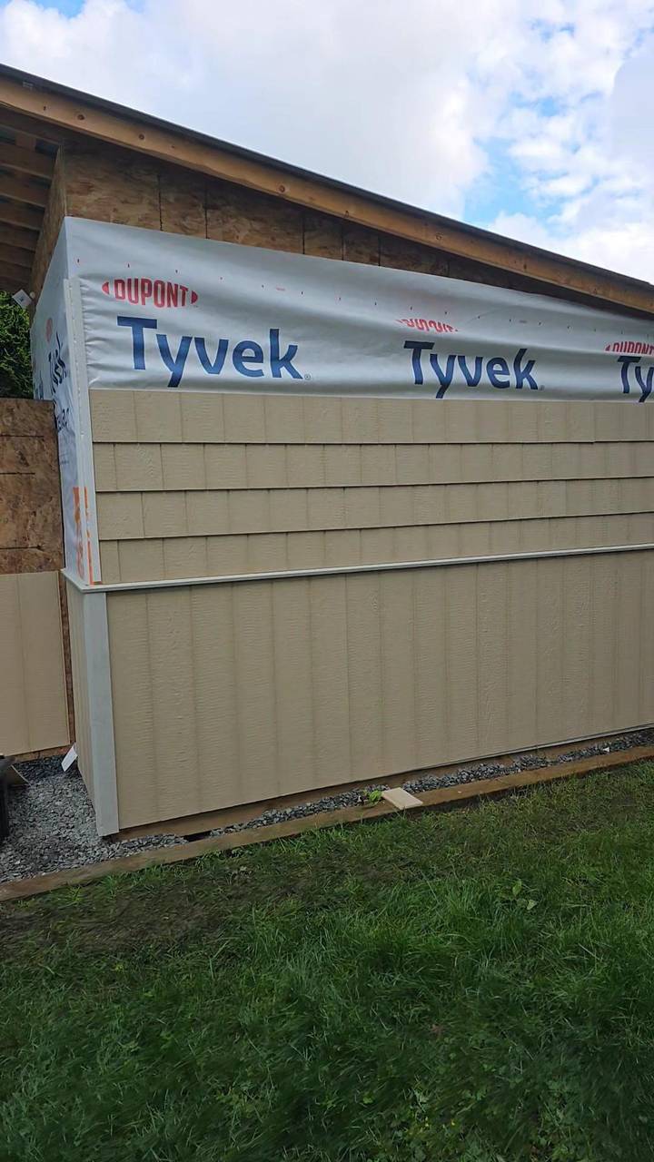 Beige siding going on over house wrap, gable still open