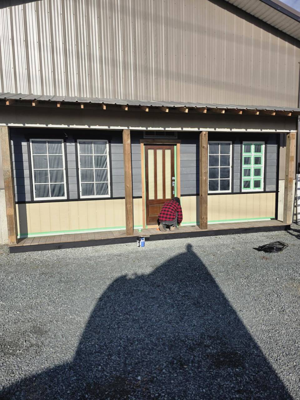 Crew fitting the door on a metal building while the wood siding goes on