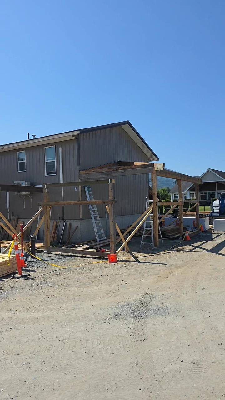 Timber porch frame going up in front of a sided house